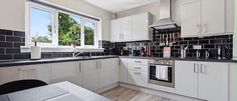A modern kitchen with white cabinets, a black countertop, and a window providing natural light.