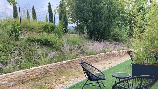 An outdoor seating area with artificial grass, stone wall, and various plants. - Room with bathroom, toilet, and terrace, 200 meters from the Saumane Golf Course (Saumane-de-Vaucluse)