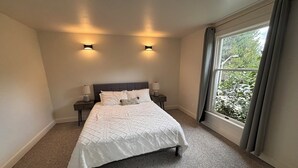 A bedroom with a bed, two bedside lamps, and a window with curtains. - Spacious 4-bedroom house in beautiful Bellevue with AC (Bellevue)