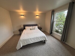A bedroom with a bed, two bedside lamps, and a window with curtains. - Spacious 4-bedroom house in beautiful Bellevue with AC (Bellevue)