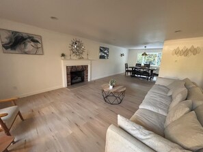 A spacious living room with a fireplace, a dining area, and a sofa. - Spacious 4-bedroom house in beautiful Bellevue with AC (Bellevue)