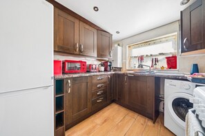 Eine kleine Küche mit Holzschränken, einer Mikrowelle, einem Toaster und einer Waschmaschine.