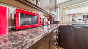 A kitchen with a granite countertop, a red microwave, and wooden cabinets. - Comfy Bishopsworth Apartment for Work & Long Stays (Bishopsworth)