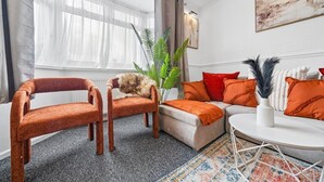 Una sala de estar con un sofá, dos sillones, una mesa de centro y una planta en maceta.