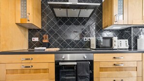 Una cocina con armarios de madera, horno de acero inoxidable, microondas y tostadora.