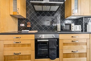 A kitchen with wooden cabinets, a stainless steel oven, a microwave, and a toaster. - HardenhuishHaus|Spacious 4BR|Group Stay|Parking (Brislington)
