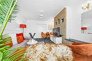 A modern living room with a sofa, a coffee table, a TV, and a dining area with chairs. - HardenhuishHaus|Spacious 4BR|Group Stay|Parking (Brislington)