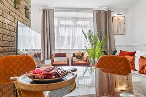 A living room with a brick wall, two armchairs, a sofa, a glass coffee table, and a potted plant. - HardenhuishHaus|Spacious 4BR|Group Stay|Parking (Brislington)