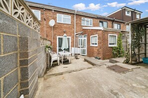 A residential property with a brick exterior, a patio with a table and chairs, and a fenced garden area. - HardenhuishHaus|Spacious 4BR|Group Stay|Parking (Brislington)