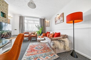 A modern living room with a sofa, chairs, a coffee table, a TV, and a floor lamp. - HardenhuishHaus|Spacious 4BR|Group Stay|Parking (Brislington)