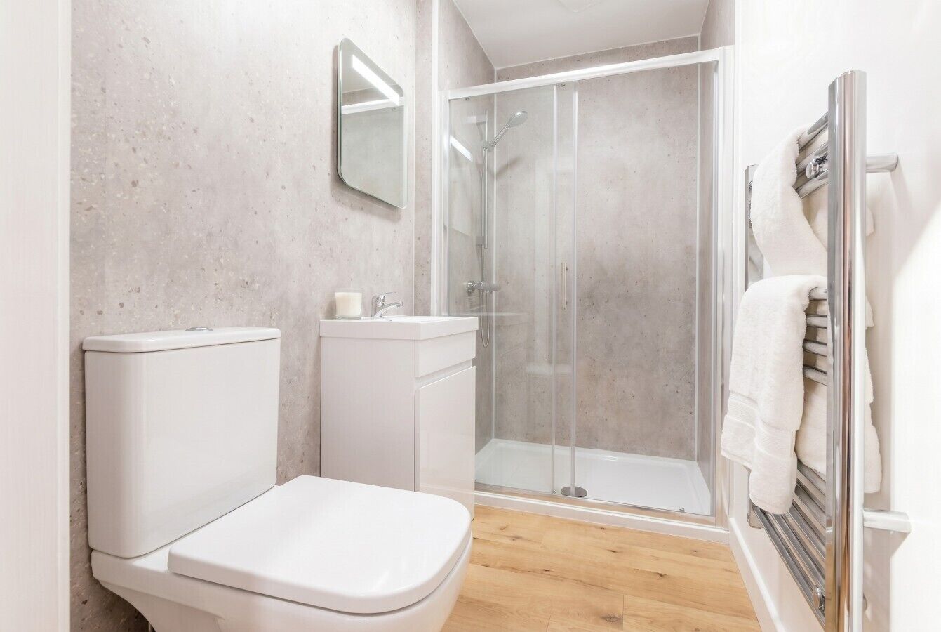 A bathroom with a toilet, a shower enclosure, and a towel rack.
