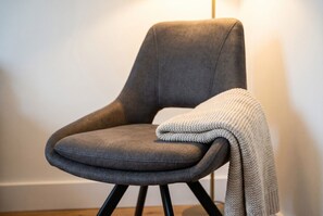 A chair with a grey upholstered seat and black metal legs, positioned against a plain wall. - 2|Burnham-on-sea|Contractors|Couple|Sleeps2|WiFi (Somerset)