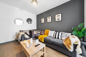 A modern living room with a grey sofa, a wooden coffee table, and a plant. - Inviting Deluxe Home: Ideal for Group|Family Stays (Brislington)