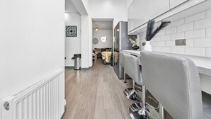 Eine moderne Küche mit Oberlicht, weiß gefliestem Fliesenspiegel und einer zentralen Kochinsel mit Barhocker.
