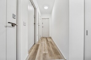 A narrow hallway with white walls and wooden flooring, leading to a door at the end. - 6|Bright Bristol Escape: Ideal for the Whole Group (Bristol)