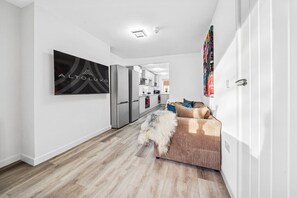 A modern kitchen with stainless steel appliances, a wooden floor, and a living area with a sofa and a fluffy dog. - 6|Bright Bristol Escape: Ideal for the Whole Group (Bristol)