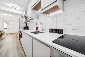 A modern kitchen with white cabinetry, a black stovetop, and a window with a view. - 6|Bright Bristol Escape: Ideal for the Whole Group (Bristol)