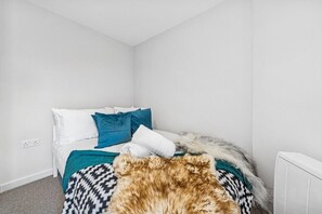 Une chambre à coucher avec un lit, des murs blancs et un radiateur blanc.