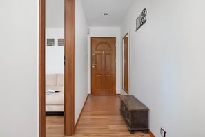 Un pasillo con una puerta de madera, un banco y un cartel en la pared.