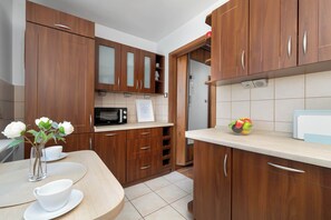 Une cuisine moderne avec des meubles en bois, un four à micro-ondes et un panier de fruits posé sur le plan de travail.