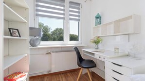 A modern, well-lit room with a white desk, black chair, and a radiator. - Spacious Apartment with Balcony | 3 Bedrooms | Workspace (Zabrze)