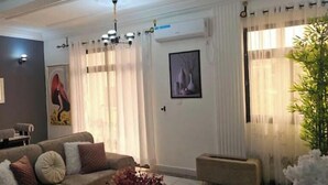 A living room with a sofa, a dining table, and a chandelier. - Cozy, Spotlessly Clean & Beautifully Appointed Luxury Apartment (Centre Region)