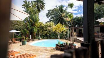 Una piscina al aire libre, sombrillas, sillones reclinables de piscina