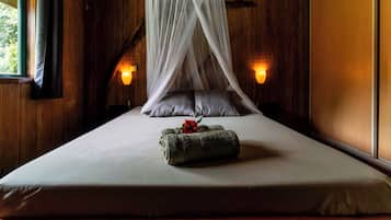 A bed with a canopy, pillows, a bedside lamp, and a decorative pillow with a flower.