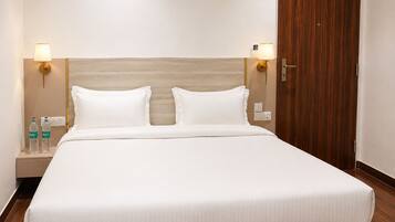 Una habitación de hotel con una cama grande, dos lámparas de noche, un cabecero de madera y un armario de madera.