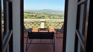 Un balcón con vista a un paisaje montañoso, una mesa y dos sillas.