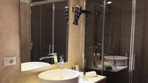 Un baño moderno con un espejo grande, un lavabo redondo, cabina de ducha y un inodoro.