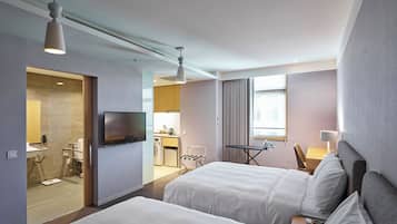 Ein Hotelzimmer mit zwei Betten, einem Fernseher, einem Schreibtisch mit Stuhl und einem sichtbaren Badezimmer durch eine geöffnete Tür.