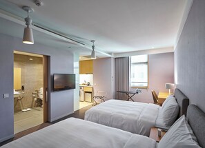 A hotel room with two beds, a TV, a desk with a chair, and a bathroom visible through an open door. - Howard Residence (Taipei)