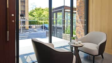 A hotel room with a view of the street, a door, a chair, and a table with a tray.