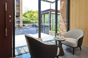 A hotel room with a view of the street, a door, a chair, and a table with a tray. - Howard Residence (Taipei)