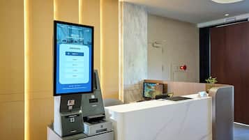 A reception area with a digital display, a reception desk, a printer, and a clock.