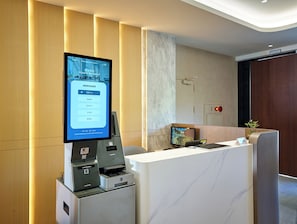 A reception area with a digital display, a reception desk, a printer, and a clock. - Howard Residence (Taipei)