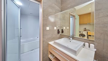 Ein modernes Badezimmer mit Duschkabine aus Glas, einem großen Waschbecken mit Spiegel und einer Holzausstattung.