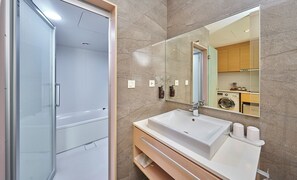 A modern bathroom with a glass shower enclosure, a large sink with a mirror, and a wooden vanity. - Howard Residence (Taipei)