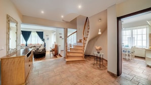 A spacious living area with a wooden staircase, a piano, and a dining area with a table and chairs. - Apartamenty Sun & Snow Villa Łokietka (Sopot)