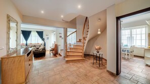 A spacious living area with a wooden staircase, a piano, and a dining area with a table and chairs. - Apartamenty Sun & Snow Villa Łokietka (Sopot)