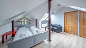 A bedroom with a bed, a red nightstand, a grey sofa, and a wooden wardrobe. - Apartamenty Sun & Snow Villa Łokietka (Sopot)