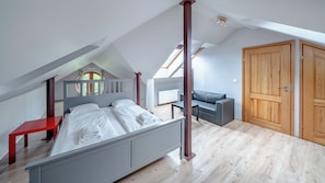 A bedroom with a bed, a red nightstand, a grey sofa, and a wooden wardrobe. - Apartamenty Sun & Snow Villa Łokietka (Sopot)