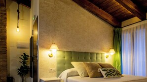 Ein Schlafzimmer mit einem Bett, Nachttischen, einer Lampe, einer Topfpflanze und einer Holzbalkendecke.