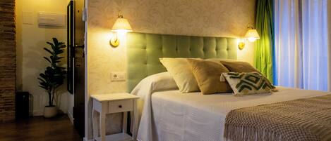 A bedroom with a bed, nightstands, a lamp, a potted plant, and a wooden ceiling.