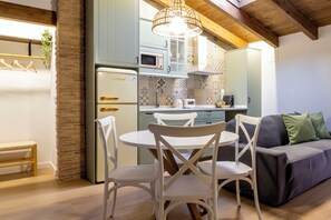 A modern kitchen with a built-in microwave, a dining area with a round table and chairs, and a sofa with cushions. - Refugi dels Somnis "Home of Dreams" - Charming Tourism in Onda (Onda)