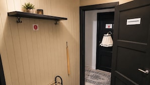 En gang med et håndklædetørrestativ, en dør med et skilt og en m ønstret måtte.