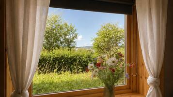 A room with a wooden window sill, a white vase with flowers, and a white spherical object on a white table.