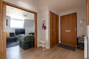 A modern living room with a sofa, television, and a small white table. - Century Court (No 10) | St Andrews (St Andrews)