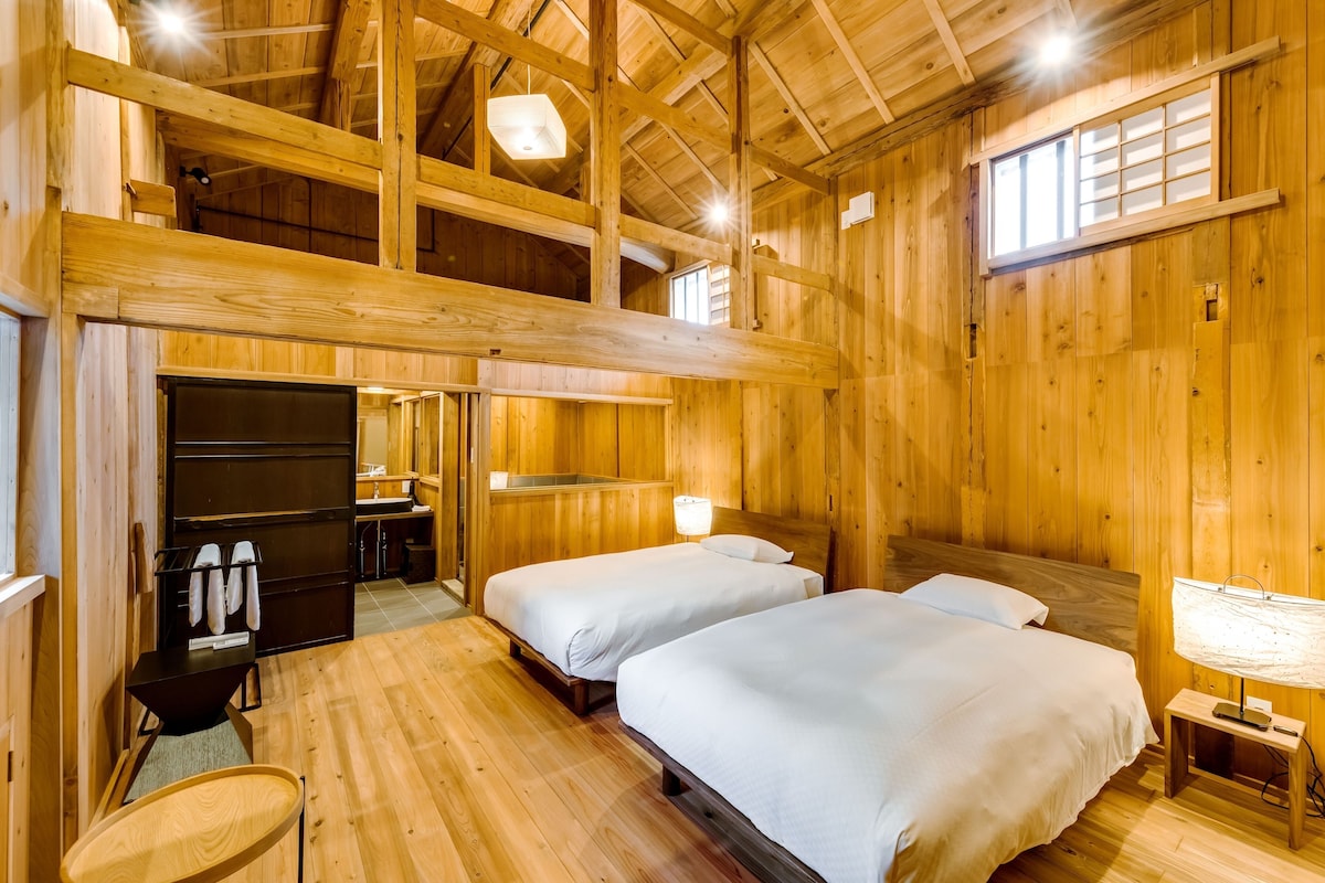 Una habitación de cabaña de madera con dos camas, un escritorio y un baño.